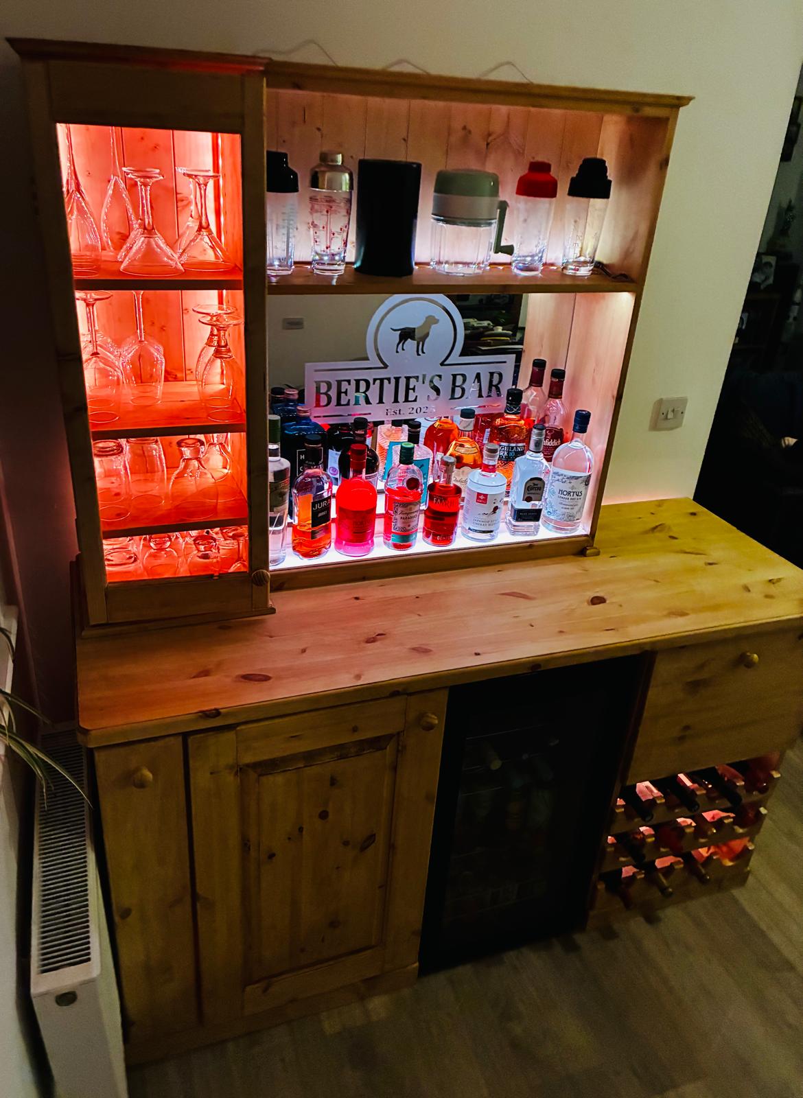 The Bideford Bar — solid pine home bar with lit shelves, glass cupboard, integrated wine fridge and red-wine rack.