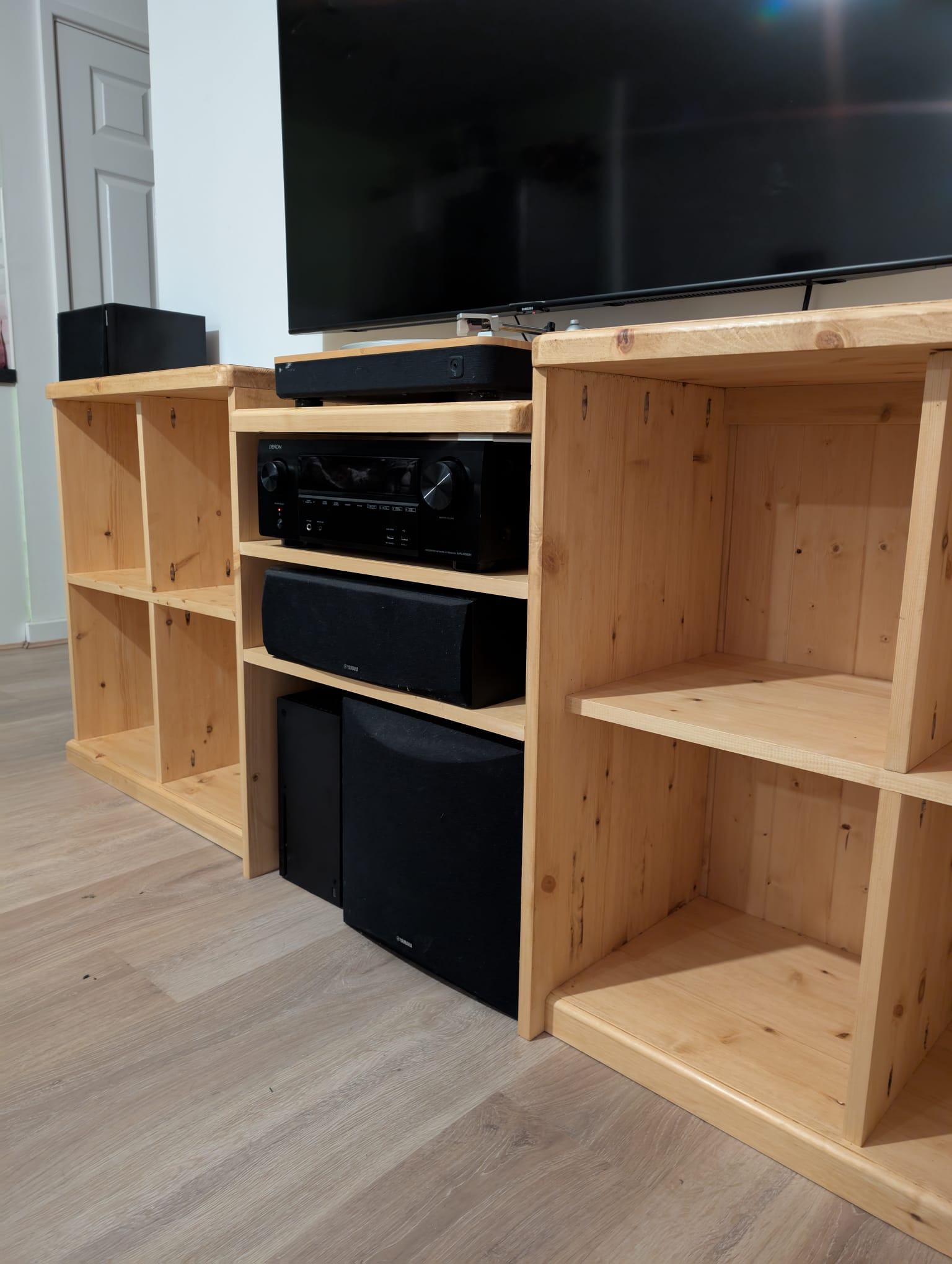 The stepped central tower of the media unit, with a turntable on top, an amplifier on the next shelf, a centre speaker below, and a subwoofer tucked in at the bottom.