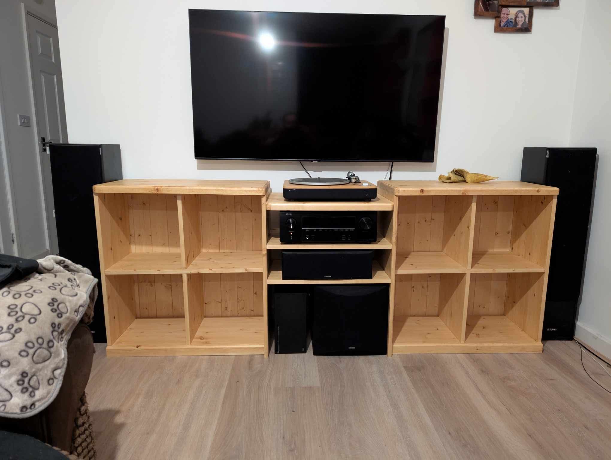 The Clovelly Media Center installed in the living room, the television above and floor-standing speakers either side, the room lit by daylight.